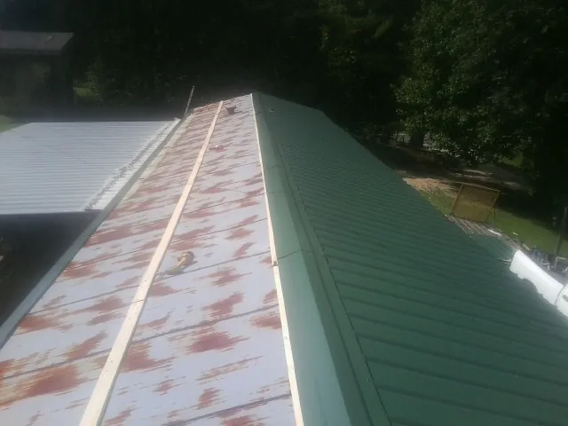 Old rusted panels beside newly installed green metal roofing — Wind Damage Roof Repair by Roofing Brothers in Hartsville